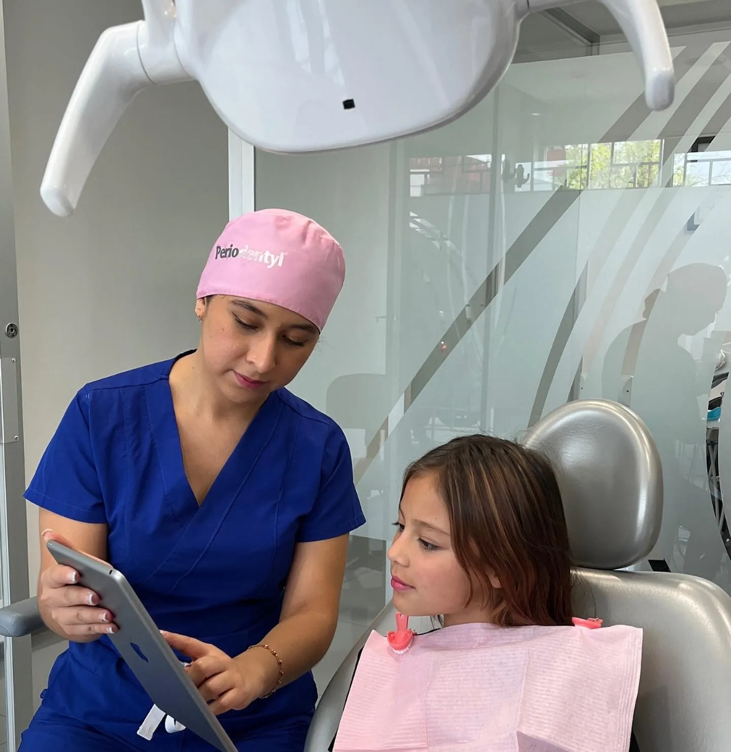 Dentista mostrando a una niña en una tableta las imágenes de su revisión